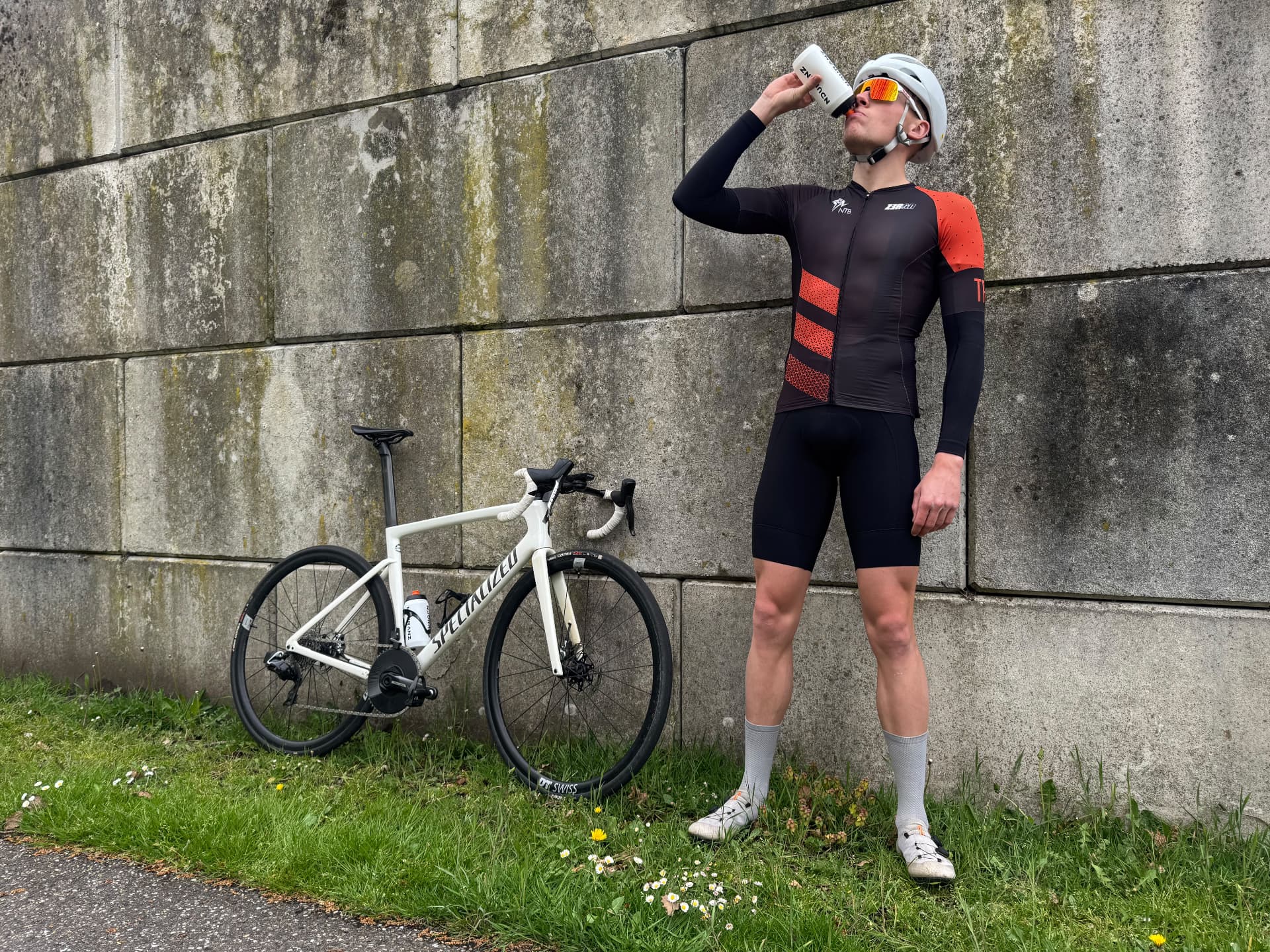 Niels van Lanen drinkt uit zijn bidon naast zijn racefiets